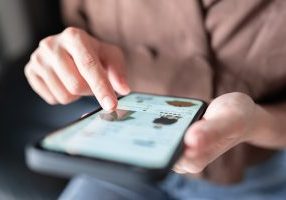 Woman online shopping on smart phone fashion clothes at home